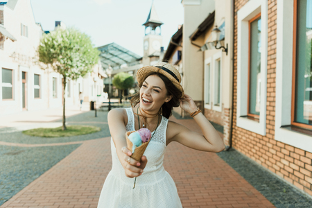 beautiful young woman eating ice cream and smiling outdoorの写真素材