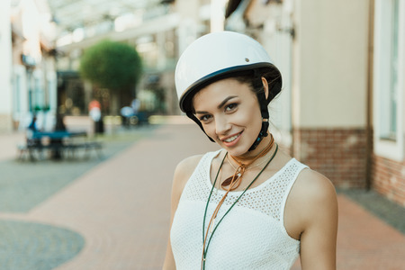 young smiling woman in helmet looking at camera outdoorsの写真素材