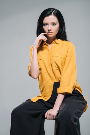 seductive brunette model in yellow blouse sitting on stool,の写真素材
