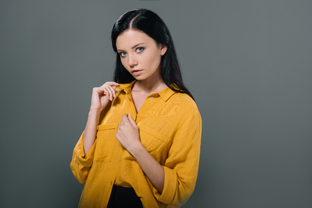 brunette woman posing in yellow blouse, isolated on greyの写真素材