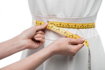 cropped view of dressmaker measuring white dress on dummy,の写真素材
