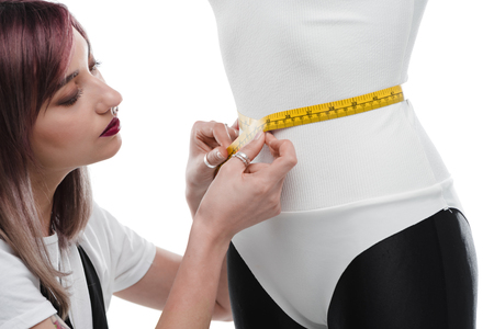 beautiful young seamstress measuring white bodysuit on dummyの写真素材