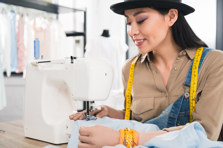 smiling asian woman working with sewing machineの写真素材