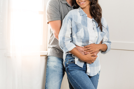happy young couple standing embracing at homeの写真素材