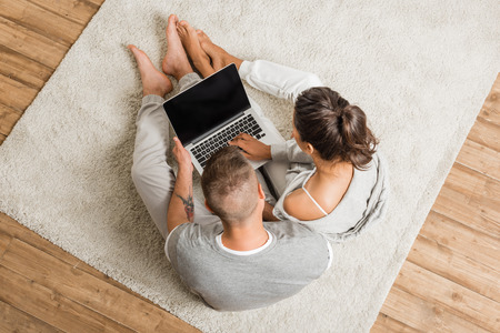 couple using laptop together while sitting on floorの写真素材