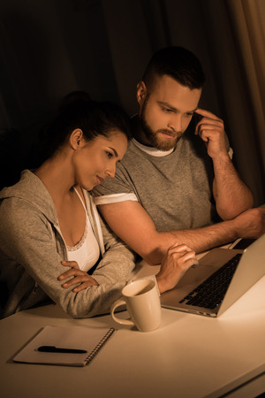 pensive couple looking at laptop while sprnding time at homeの写真素材