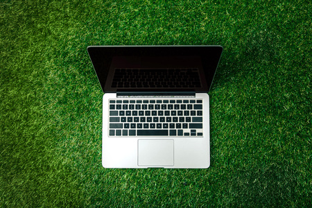 top view of opened laptop with blank screen on green lawnの写真素材