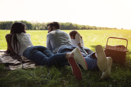 back view of family resting on blanket while spending time together at countrysideの写真素材