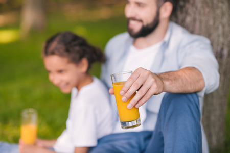 happy father and daughter holding glasses with fresh juiceの写真素材