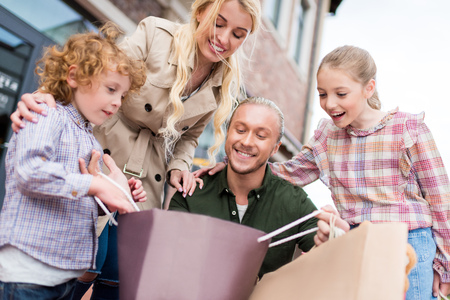 caucasian family looking into shopping bag on the streetの写真素材