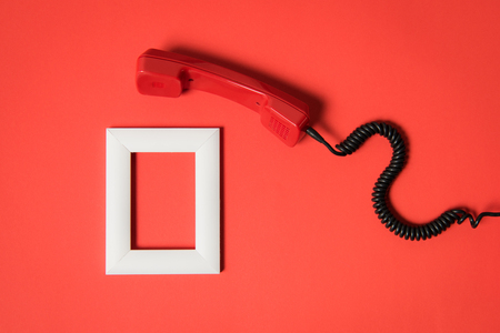 Close-up view of vintage telephone handset and white frame isolated on redの写真素材