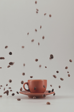 ceramic coffee cup with falling coffee grains isolated on greyの写真素材