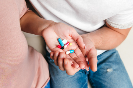 young couple holding various pills on palmsの写真素材