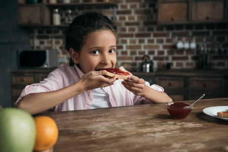 girl eating toast with homemade jam at homeの写真素材