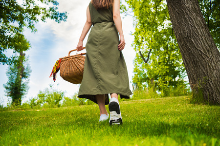 girl holding picnic basket while walking in parkの写真素材
