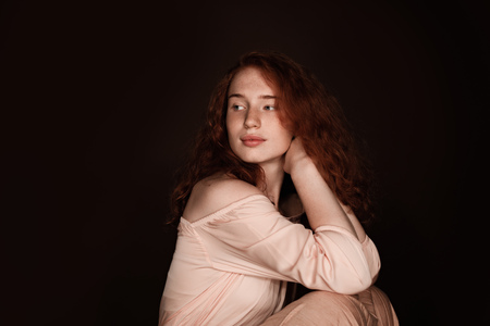 attractive redhead woman sitting in beige clothesの写真素材