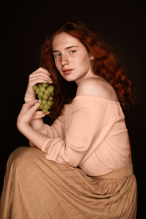 beautiful redhead woman holding green grapesの写真素材