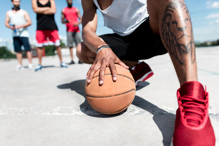 man holding basketball ball while sitting on courtの写真素材