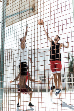 athletic men playing basketball together on courtの写真素材
