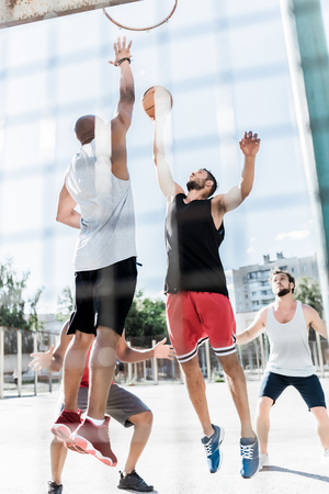 athletic men playing basketball together on courtの写真素材
