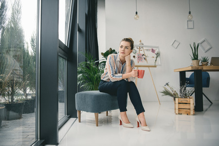 thoughtful businesswoman on coffee break in modern officeの写真素材