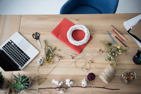 florist workplace with dry flowers, wreath and laptop in modern officeの写真素材