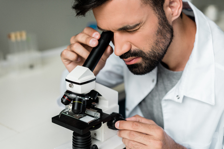 male scientist in white coat working with microscope in chemical labの写真素材