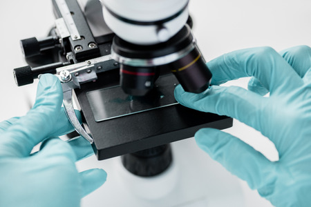 scientist working with microscope and glass microscope slide in labの写真素材