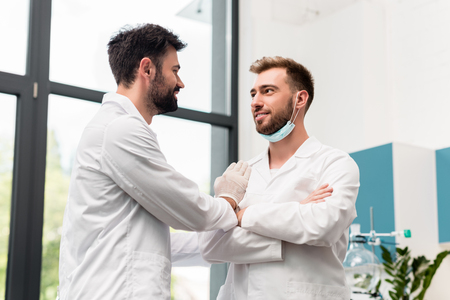 handsome young male scientists in white coats talking and smiling each other in chemical labの写真素材