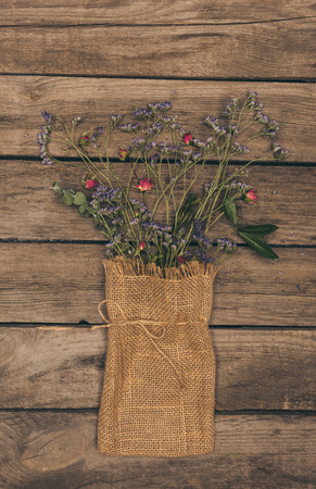 beautiful dried flowers arranged in sack bag on wooden table topの写真素材