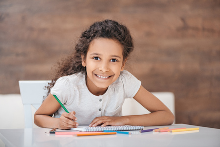 adorable african american girl drawing with colorful pencils