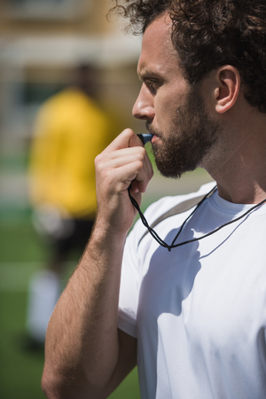 soccer referee whistling in whistle on soccer pitch during gameの写真素材