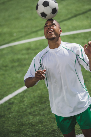 african american soccer player holding ball on headの写真素材