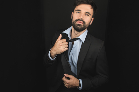 handsome bearded businessman posing in tie and black suitの写真素材
