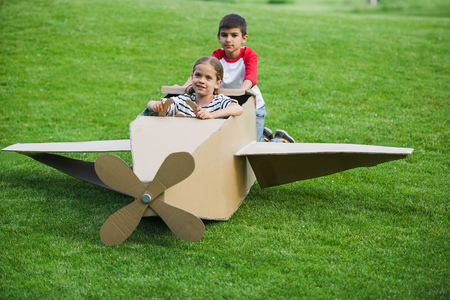 little friends playing with toy plane on green lawn in parkの写真素材