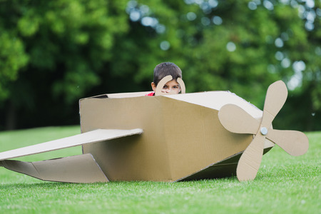 little boy pretending to be pilot sitting in diy airplane while playing in parkの写真素材