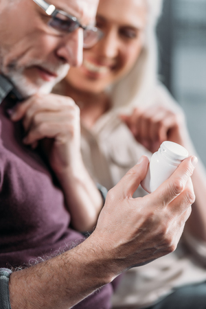 senior couple looking at pill bottle in handの写真素材