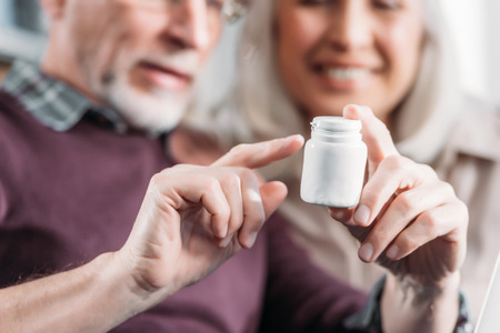 senior man pointing at pill bottle in handの写真素材