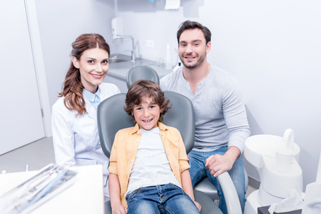 smiling boy with father and dentist at dentist officeの写真素材