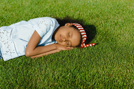 little african american girl sleeping on green grassの写真素材