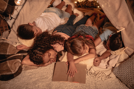 little children sleeping after reading book at homeの写真素材