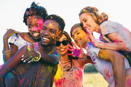 happy friends piggybacking together at holi festivalの写真素材