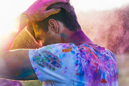 caucasian man with powder on clothing during holi festival