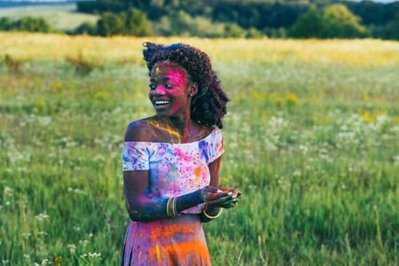 african american woman with colorful powder in hands looking away at holi festivalの写真素材