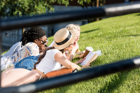 students lying on green grass while studying in parkの写真素材