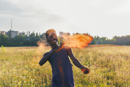 happy african american man throwing colorful powder at holi festivalの写真素材