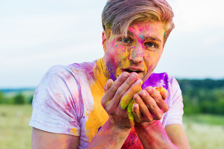 man holding colorful powder in hands and looking at camera at holi festivalの写真素材