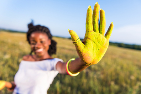 young african american woman showing palm with yellow paint at holi festivalの写真素材