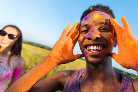 happy african american man with colorful paint of face smiling and looking away at holi festivalの写真素材