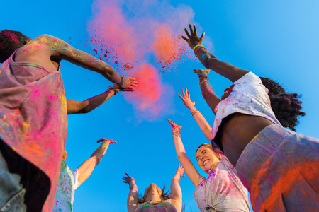 young multiethnic friends having fun with colorful powder at holi festival of colorsの写真素材